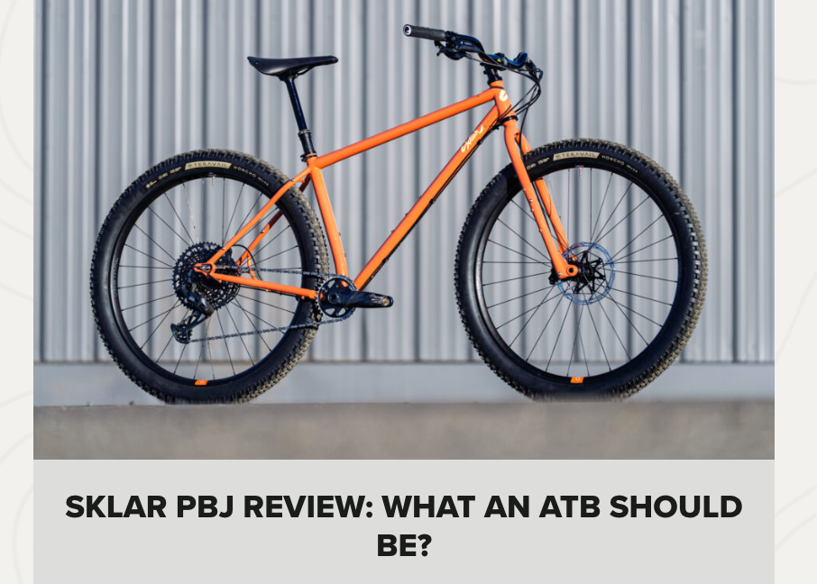 Orange mountain bike with text about a Sklar PBJ review on a gray background